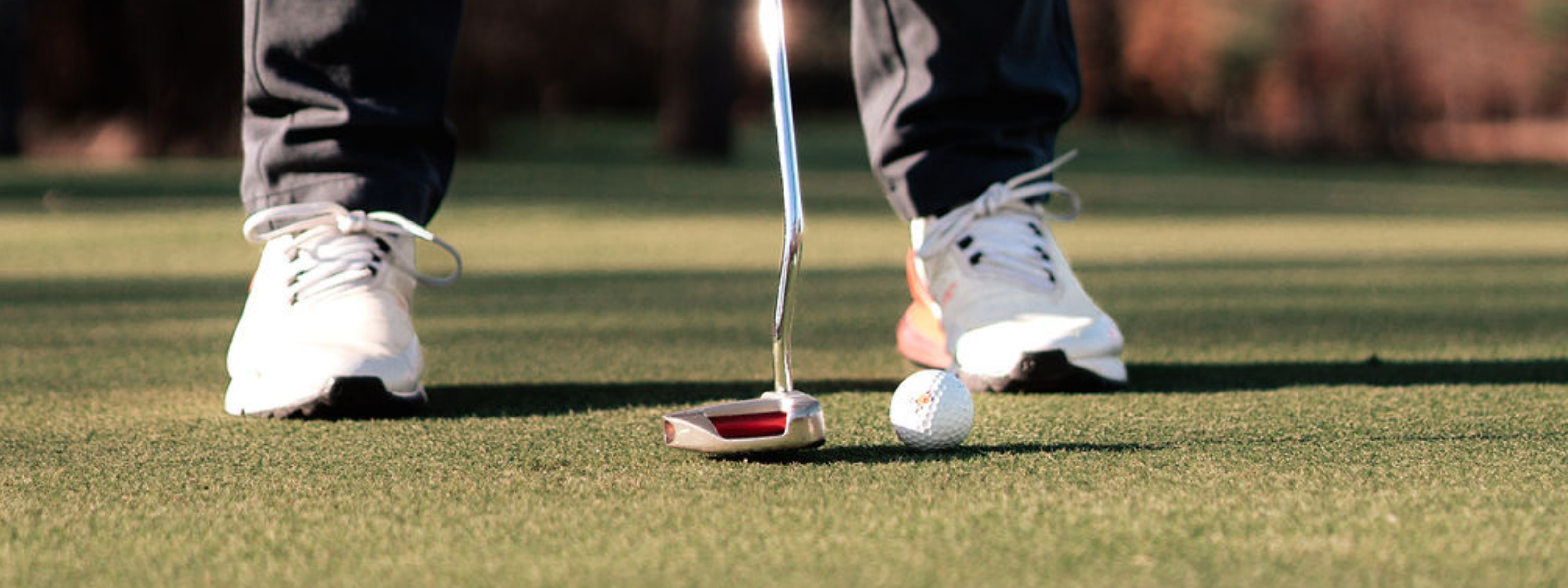 Feet of a golfer while putting a Sportr golf ball on a green.
