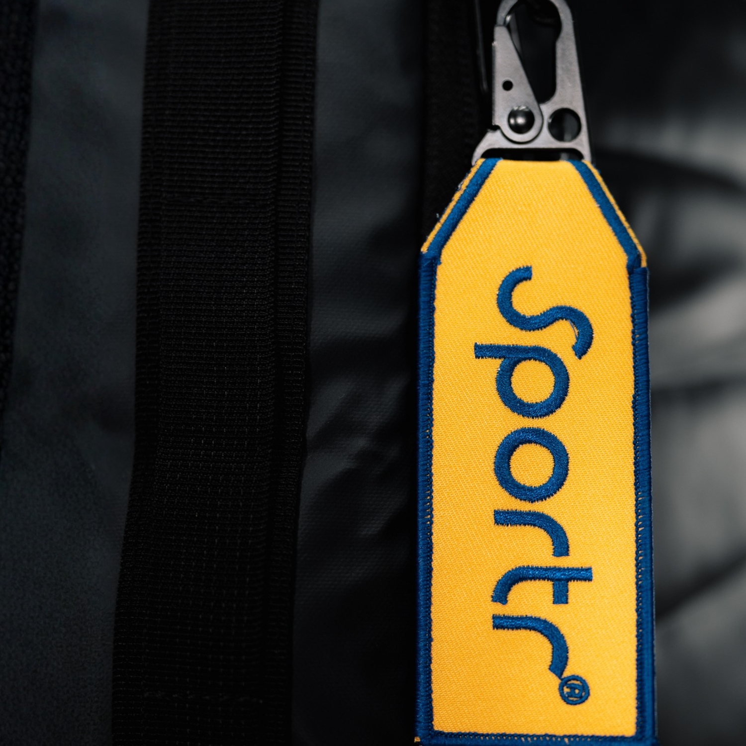 Yellow tag with 'Sportr' branding attached to a black Golf Travel Bag.